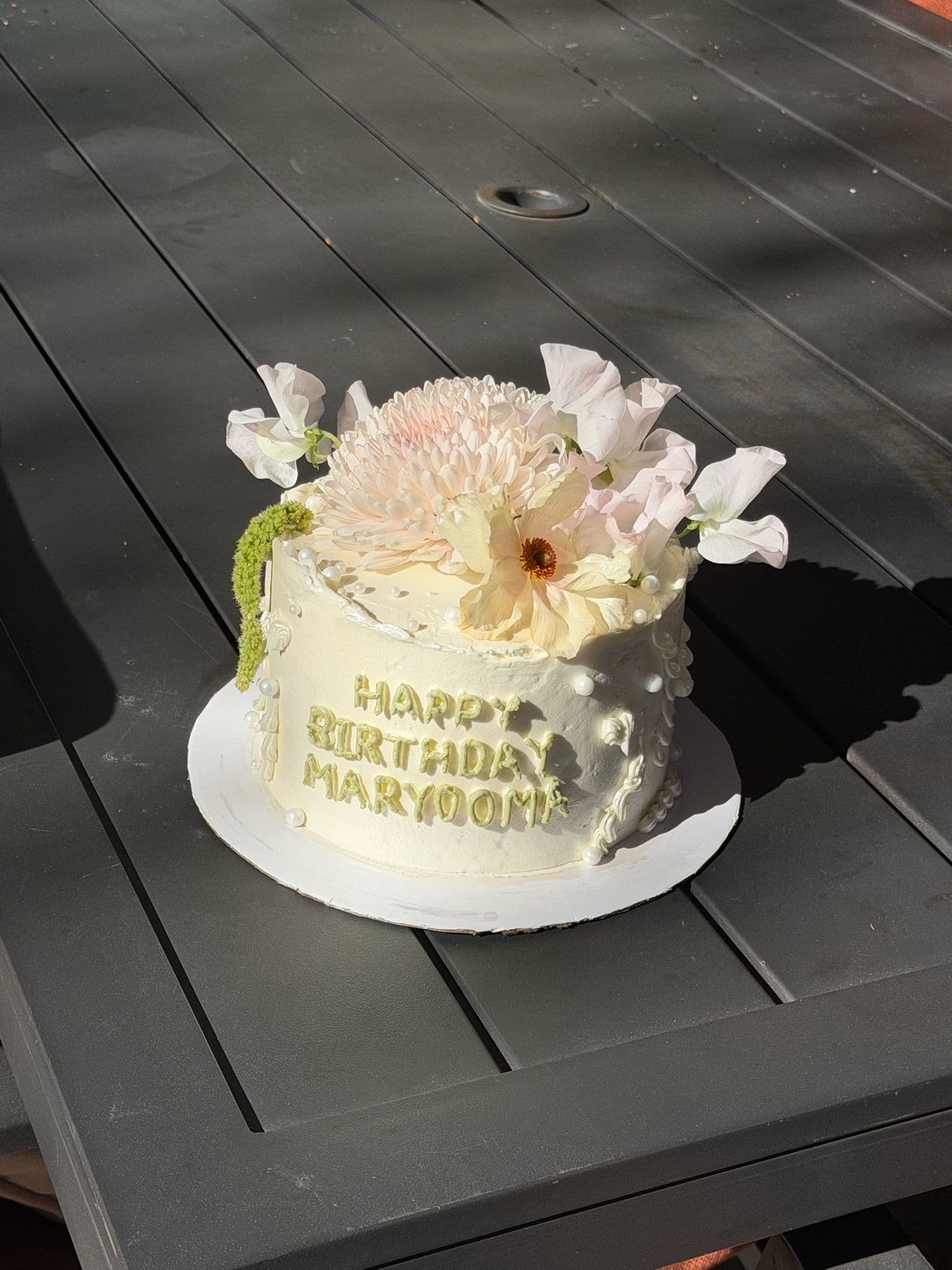 Small cake with pearl piping, green lettering and a blush chrysanthemum crown