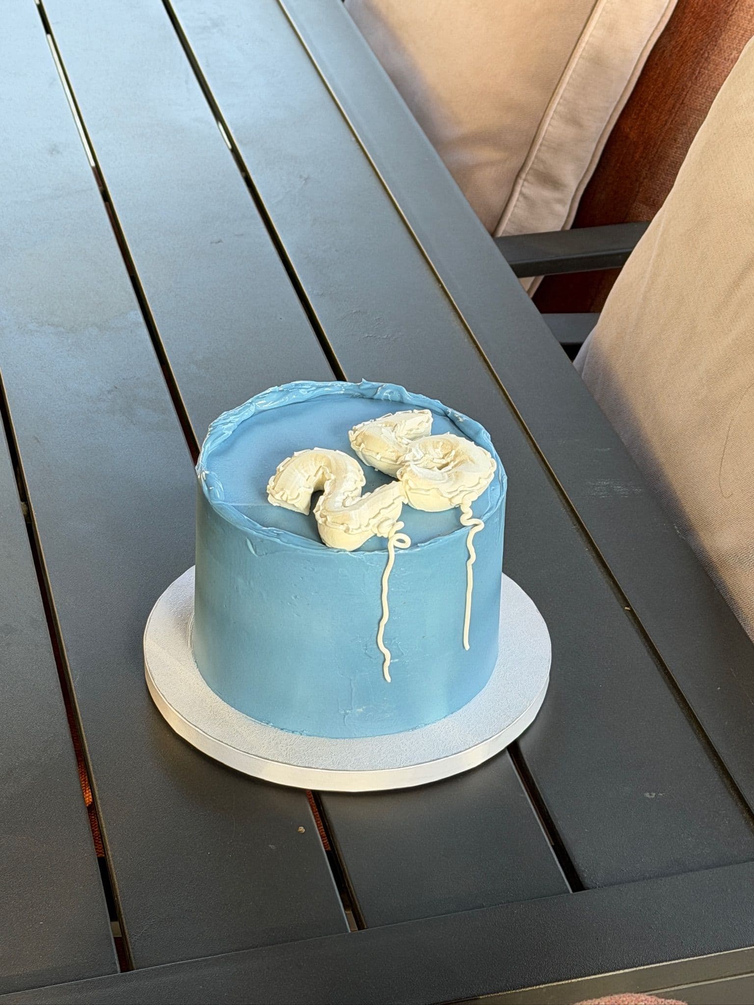 Round cake in pale blue buttercream finished with a caramel drip and banana slices