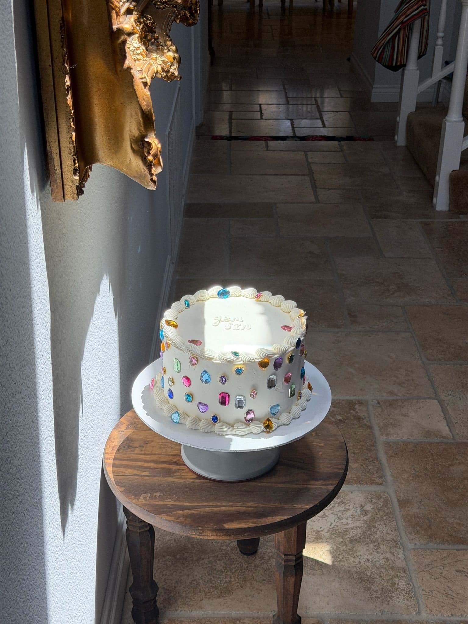 Petite cake speckled with pastel buttercream dots on a small pedestal stand