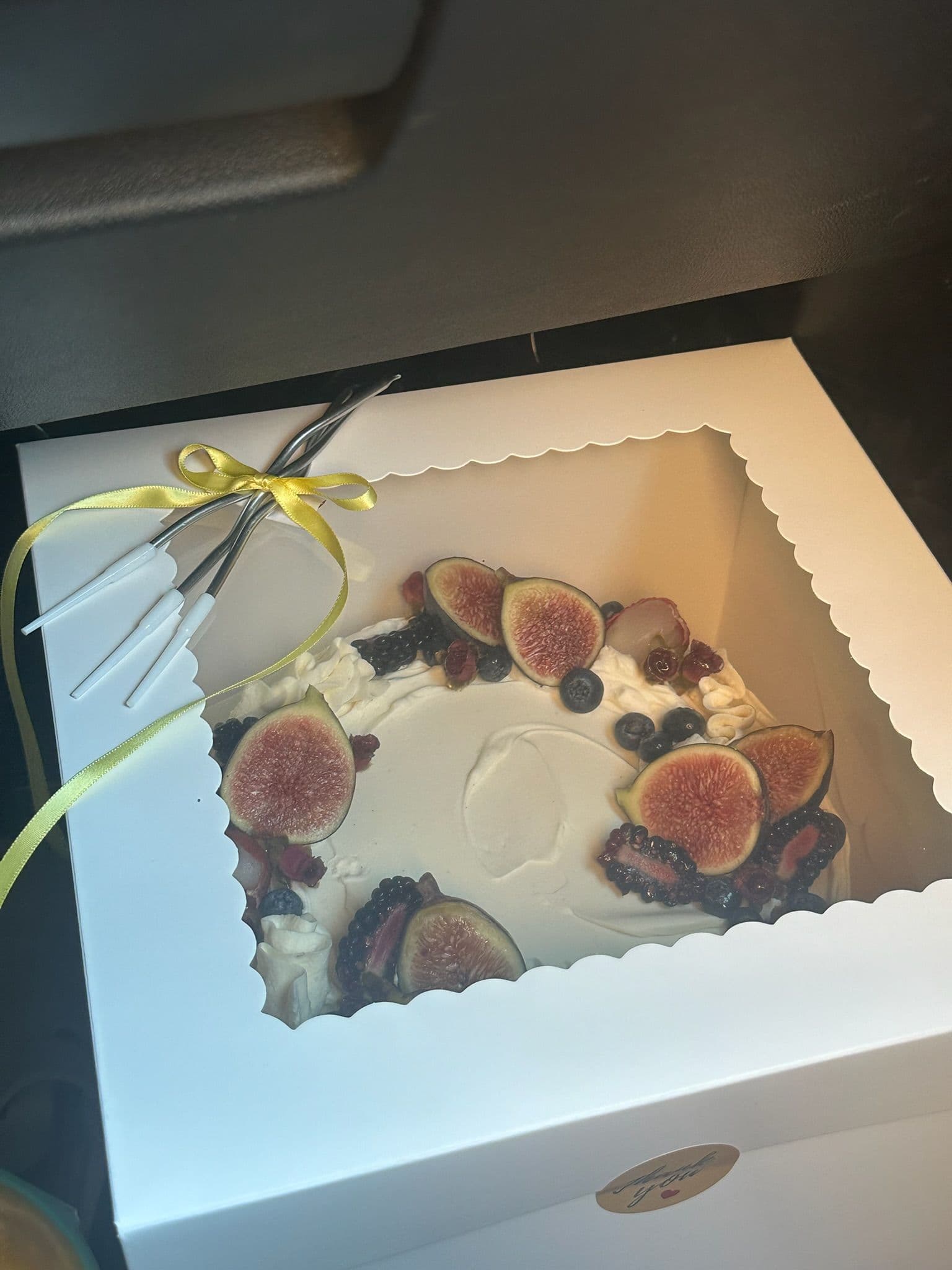 Cake crowned with halved figs, blackberries and blueberries, boxed with a yellow ribbon