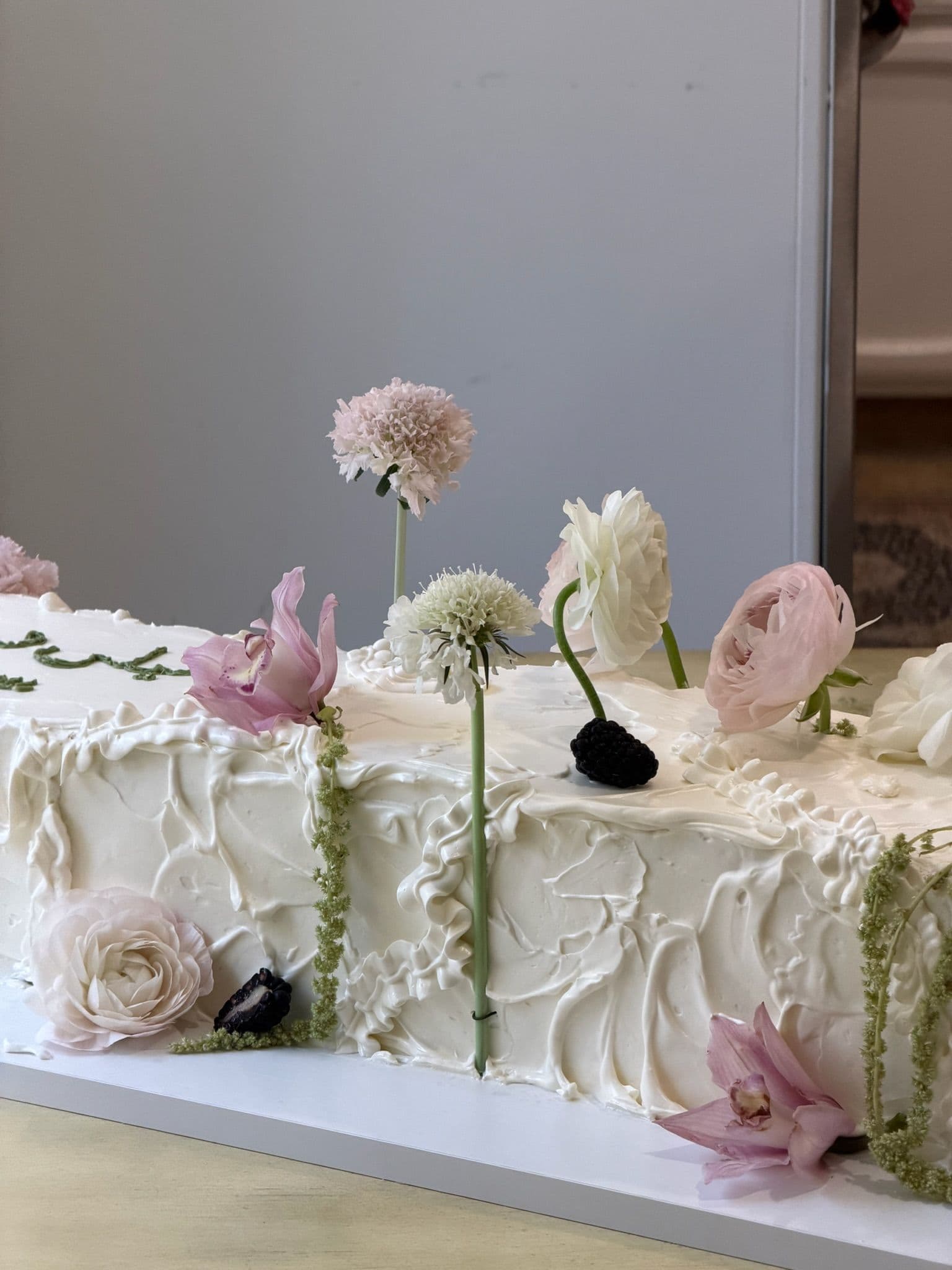 Long sheet cake detail with pale roses, scabiosa and blackberries set into the buttercream