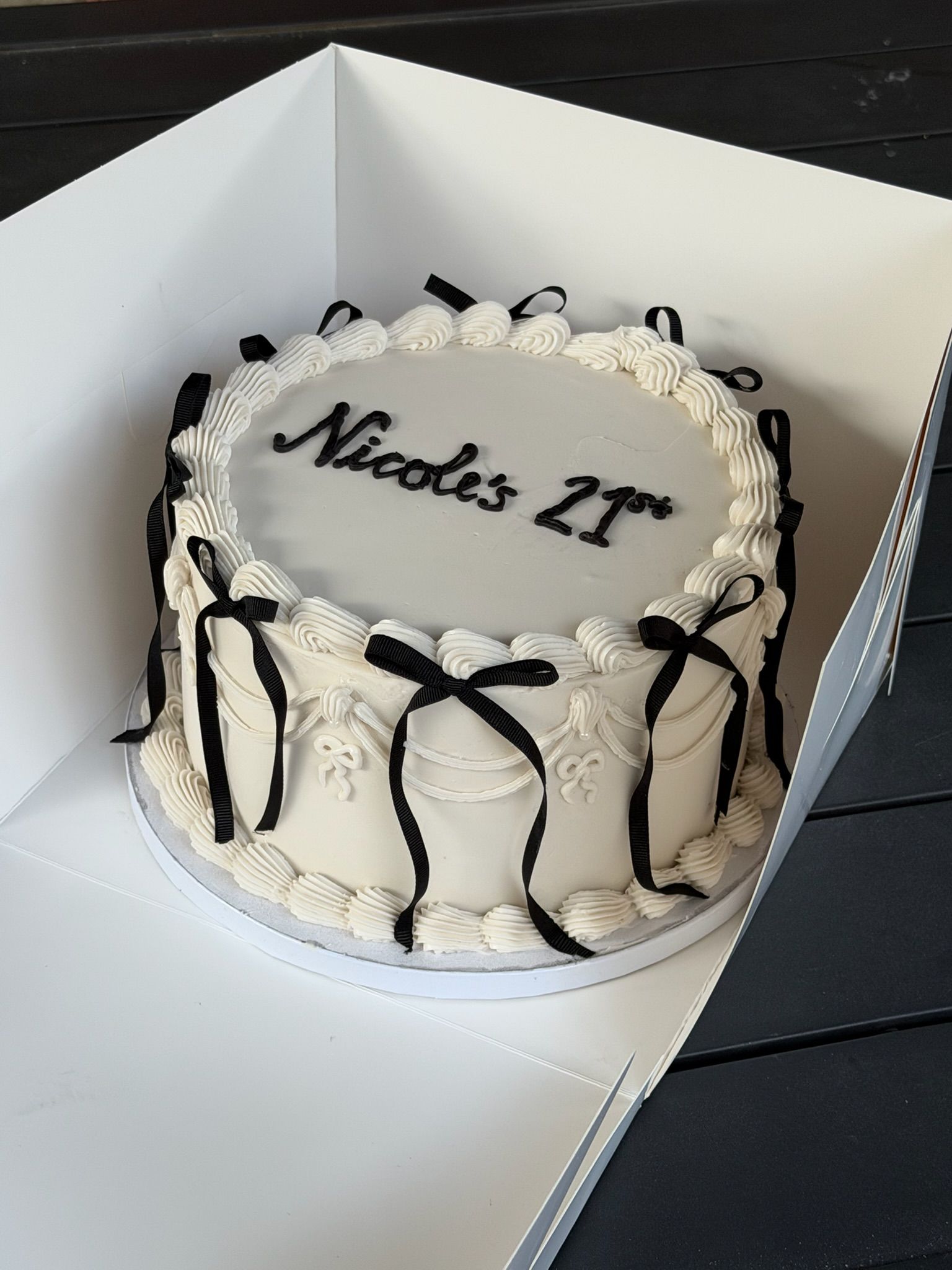 Vintage piped cake in ivory with black grosgrain bows and dark script lettering